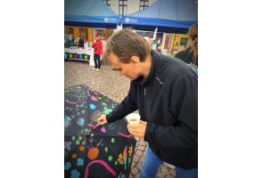 Mężczyzna maluje kolorowy parasol podczas plenerowej akcji artystycznej na rynku w Skoczowie.