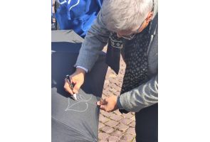 Mężczyzna rysuje białym markerem liść na czarnym parasolu podczas plenerowej akcji na rynku w Skoczowie.