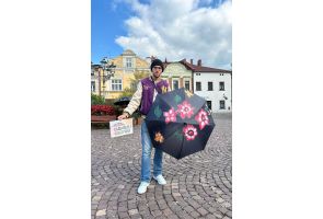 Uczeń prezentuje pomalowany parasol z kwiatowym wzorem i kartkę 