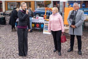 Kobieta przemawia przez mikrofon podczas akcji artystycznej na rynku w Skoczowie.